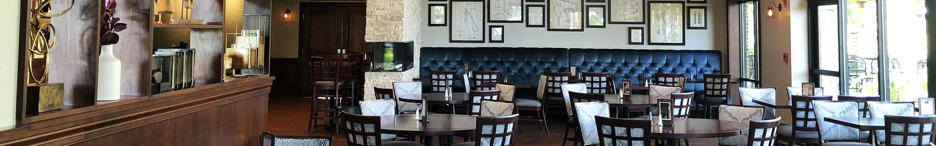 Interior of a restaurant featuring wooden tables, blue tufted seating, and framed artwork on the walls.