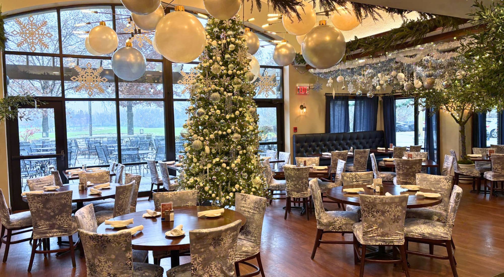 Festively decorated restaurant with a Christmas tree, snowflake-patterned chairs, and holiday ornaments.